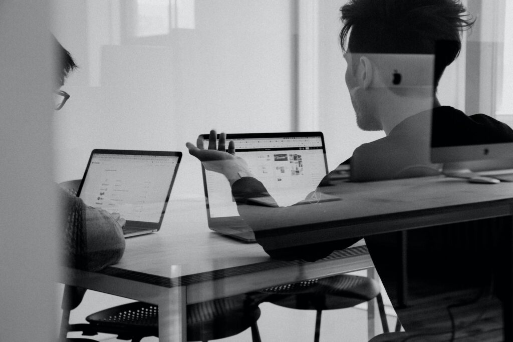 Deux hommes élaborant une stratégie digitale dans un bureau en monochrone.